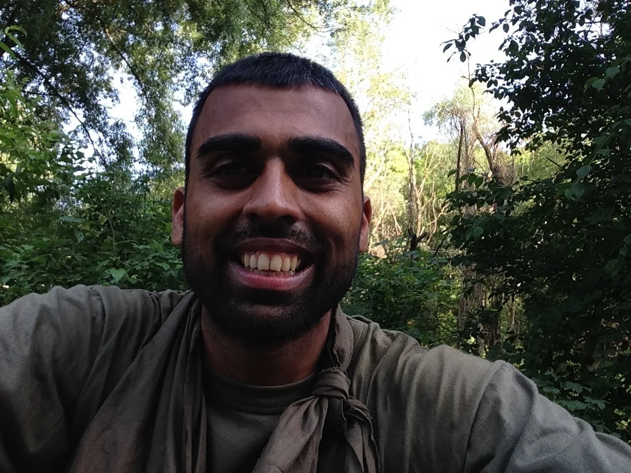 Deepak Shukla smiling in a green T-shirt among dense woodland