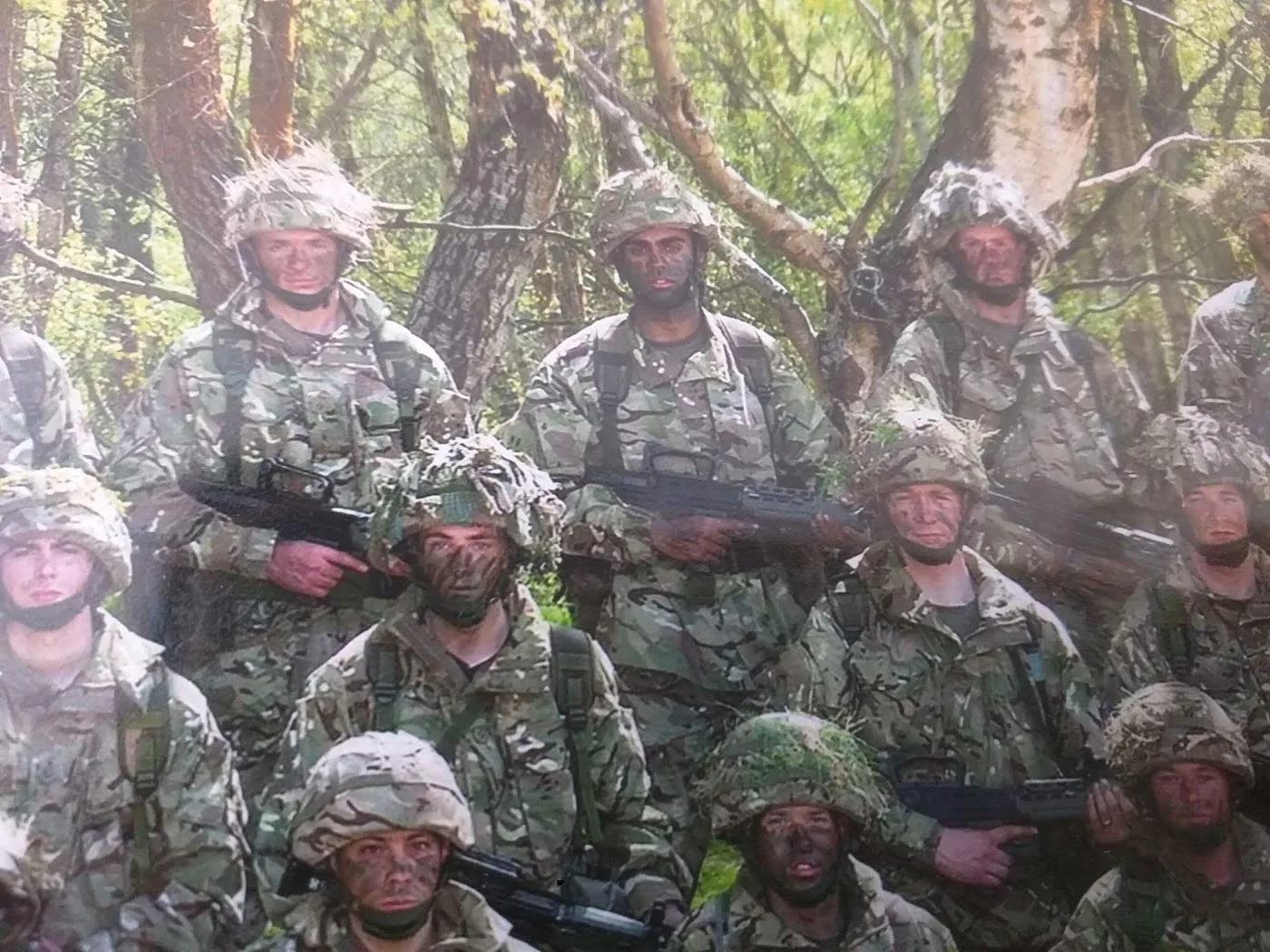 A group wearing camouflage with field equipment in woodland.