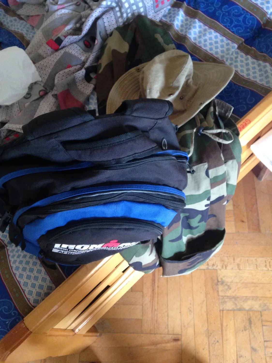 Blue and black bag beside a fabric hat and camouflage material indoors