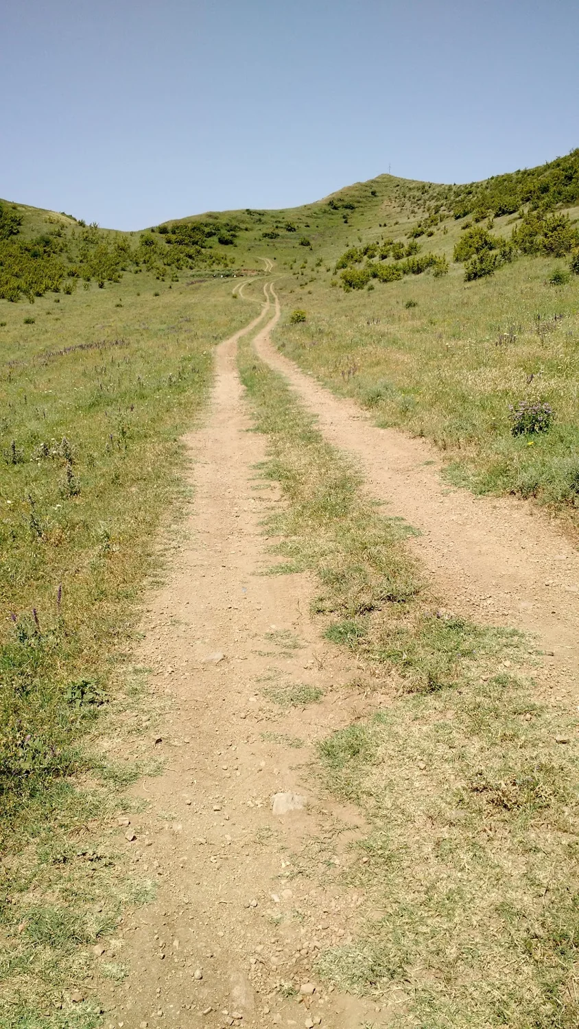 Narrow earth path climbing between grassy hills