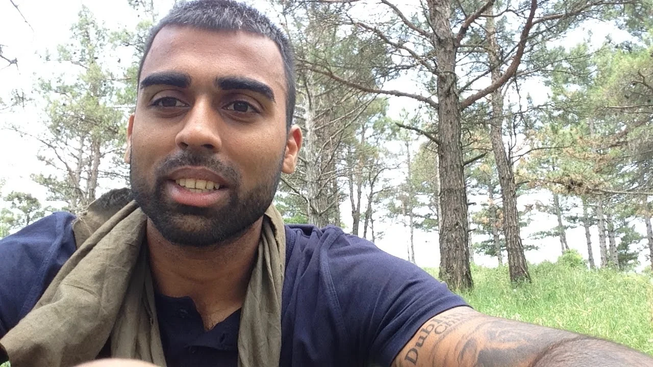 Deepak Shukla in a dark top with a cloth over his shoulder among pine trees