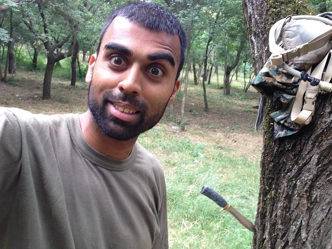 Deepak Shukla beside a tree with a hanging rucksack in woodland