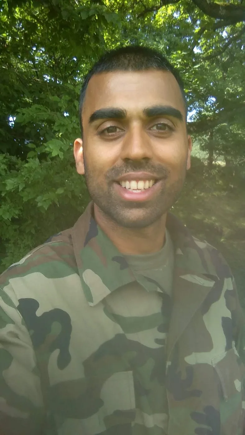 Deepak Shukla wearing camouflage uniform outdoors with trees behind him.