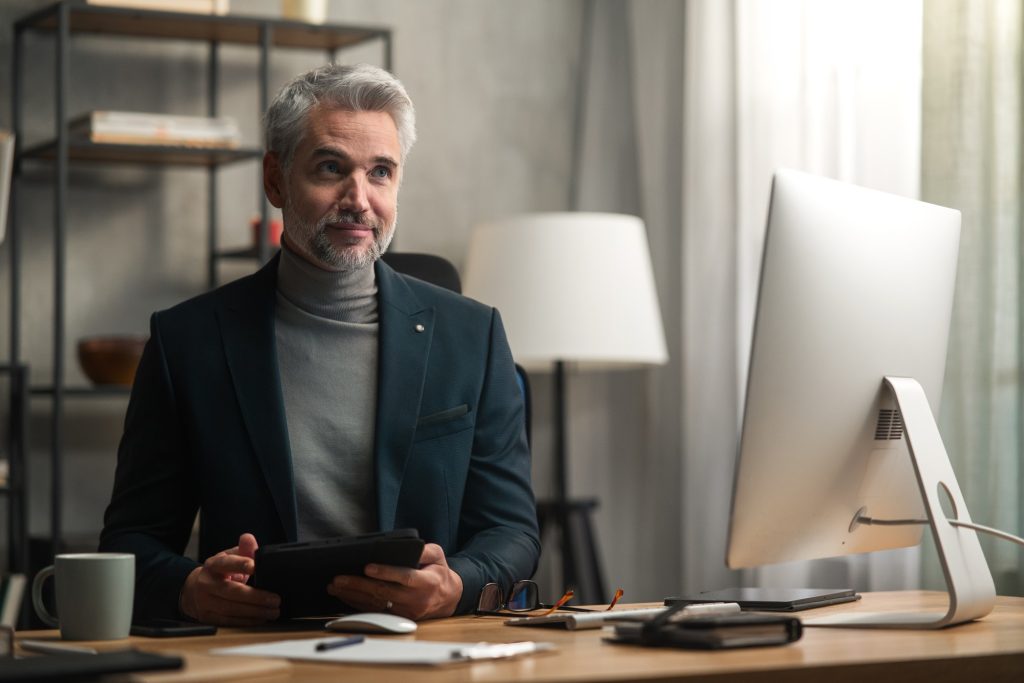 Mature businessman indoors in office, working on tablet