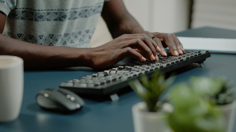 Close up of hands using computer keyboard and listening to music